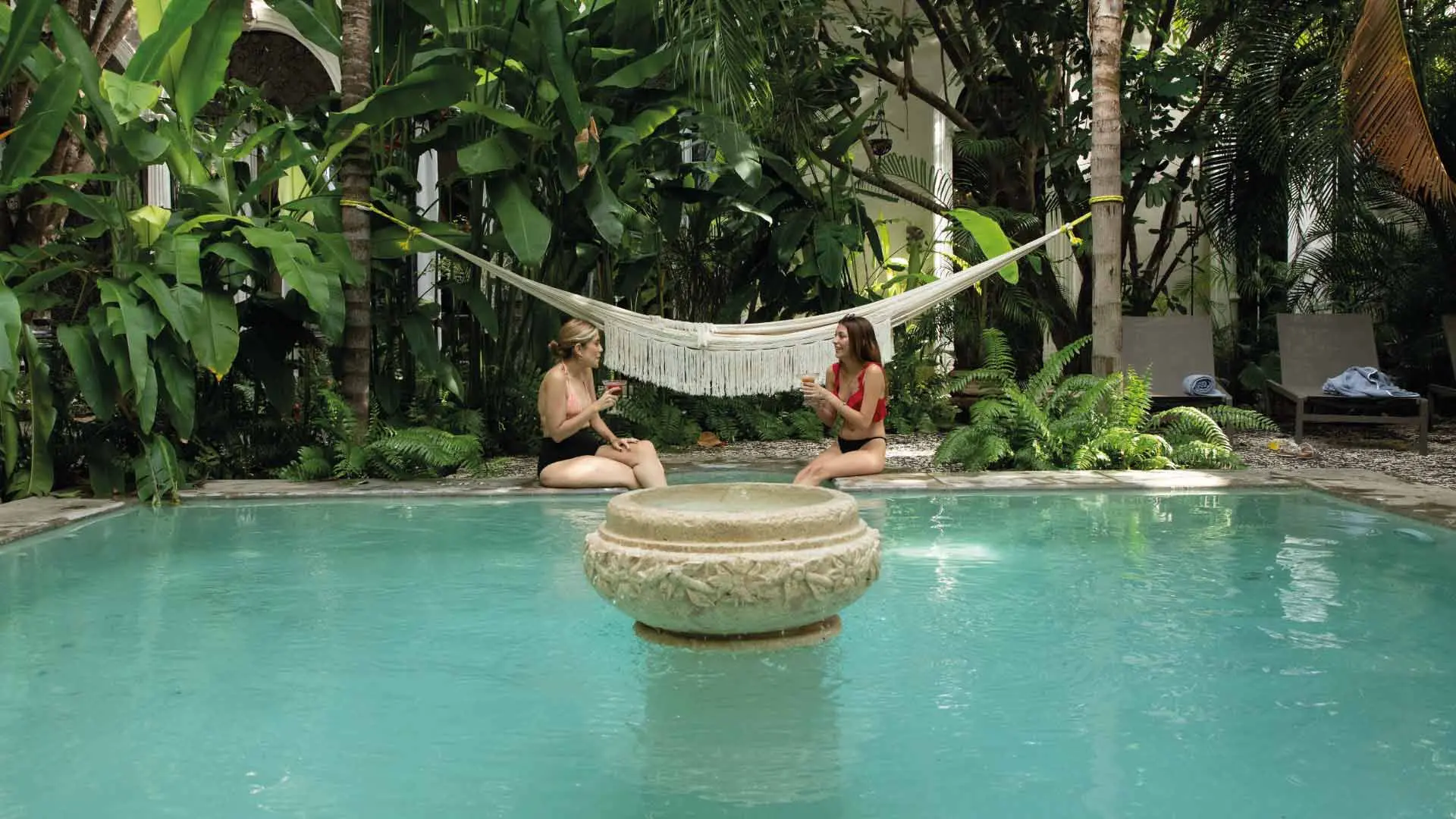 Huéspedes relajándose y disfrutando del sol en la piscina del hotel, rodeados de un ambiente tranquilo y refrescante, perfectos para un día de descanso.